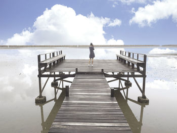 Rear view of man on pier over sea against sky