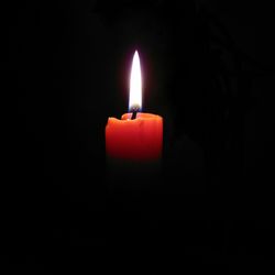 Close-up of illuminated candle in darkroom