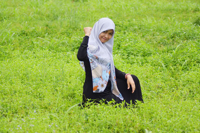 Portrait of smiling woman clenching fist on grassy land