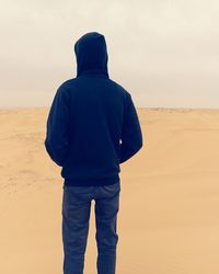 Rear view of man standing on sand dune