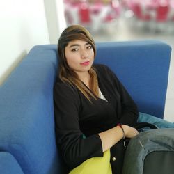 Portrait of young woman sitting on sofa