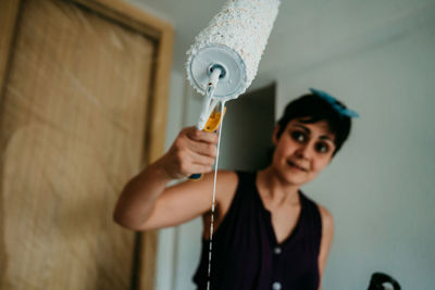 Portrait of woman holding camera at home