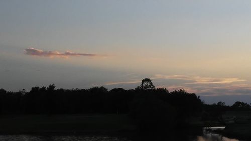 Silhouette trees by lake against sky during sunset