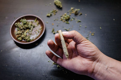 Cropped hands of man holding marijuana joint