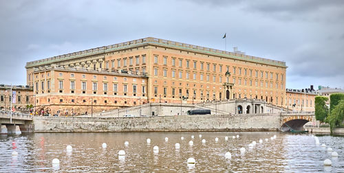 Buildings by river against sky