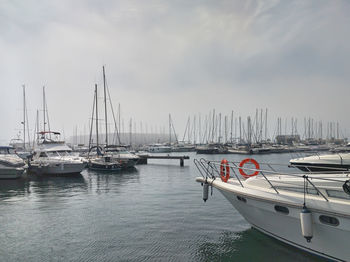 Sailboats moored on harbor against sky