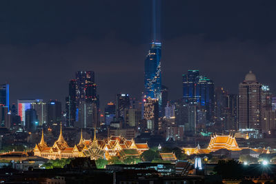 Illuminated buildings in city against sky at night