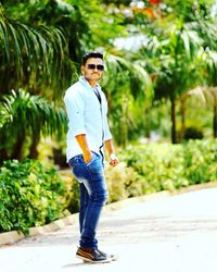 Portrait of young man wearing sunglasses standing on footpath