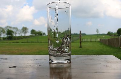 Close-up of glass on table against sky