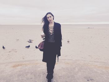 Portrait of woman holding disposable cup at beach