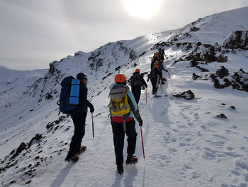 Rear view of people on snowcapped mountain against sky