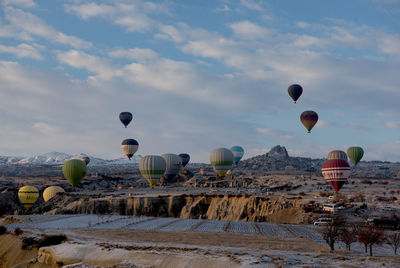Hot air balloons flying over land against sky