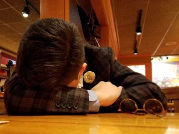 Rear view of boy sitting on table