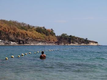 Rear view of man in sea against clear sky