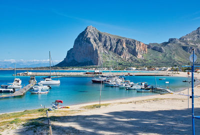 Sailboats moored in sea against blue sky