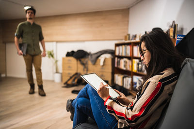 Young woman using mobile phone while sitting on book