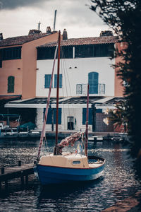 Sailboats moored on sea by city against sky
