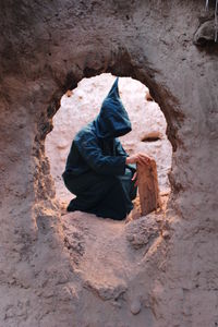 Rear view of man sitting on rock