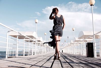 Rear view of woman walking on pier over sea