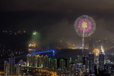 Firework display over city by gwangandaegyo at night