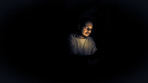 Portrait of young man sitting in darkroom