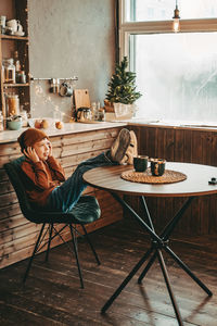 Boy in headphones listening to music with his feet on the table