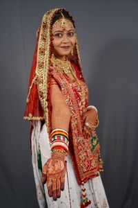 Bride showing hand with henna tattoo over gray background