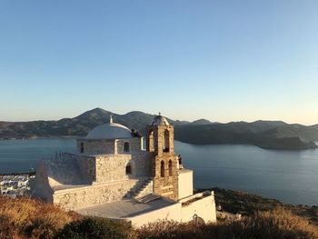 Buildings by sea against clear sky