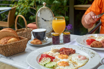 Delicious breakfast served with a cup of cappuccino. there is a clock on a table showing 10.15 am