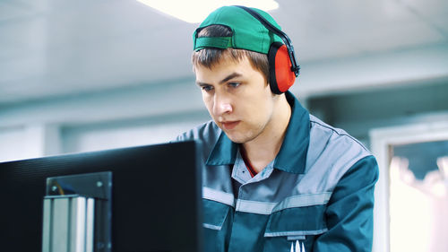 Portrait of an employee of an enterprise, factory. a worker in red headphones from noise, looks at