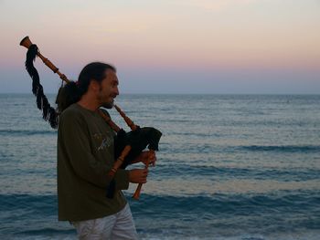Full length of woman standing on beach against sky during sunset