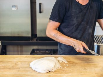 Midsection of man making sourdough breadat table