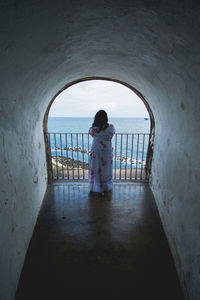 Rear view of woman standing against balcony in building