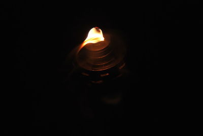 Close-up of illuminated candle in darkroom