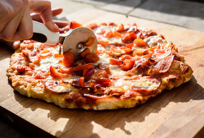 Close-up of hand holding pizza on cutting board