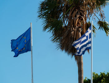 Low angle view of flags against clear blue sky