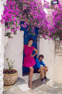 Man with a woman sitting on the steps of a blue wooden door with pink flowers in turkey on  street