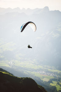 View of man paragliding over landscape against sky