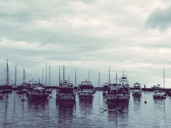 Sailboats moored in sea against sky