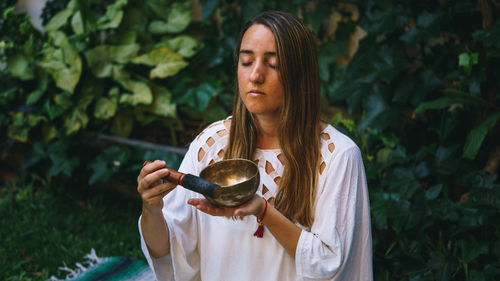 Young woman holding mortar and pastel while meditating sitting outdoors