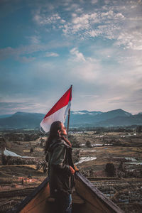 Rear view of woman standing on landscape against sky