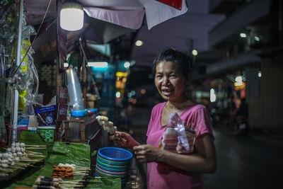 Portrait of woman buying street food at night