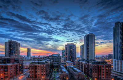 Illuminated cityscape against sky at sunset