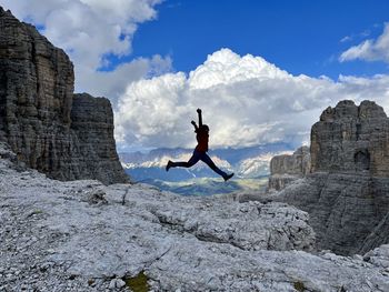 Rear view of man jumping on rock