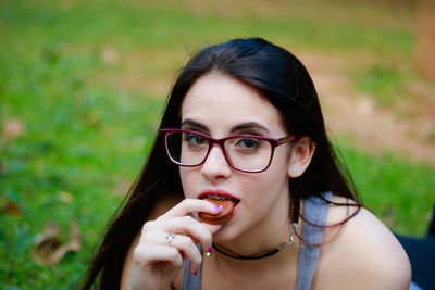 Close-up portrait of young woman eating biscuit outdoors