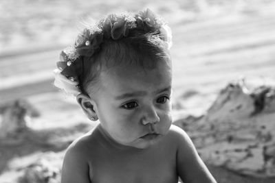 Cute girl wearing flowers while looking away at beach