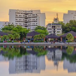 Reflection of buildings in lake against sky in city