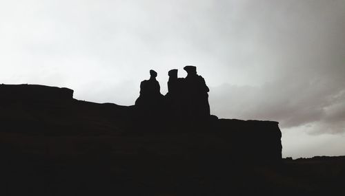 Low angle view of silhouette man on rock against sky