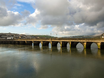 Arch bridge over river against sky