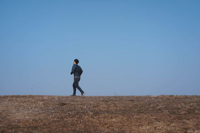 Man walking on land against clear sky